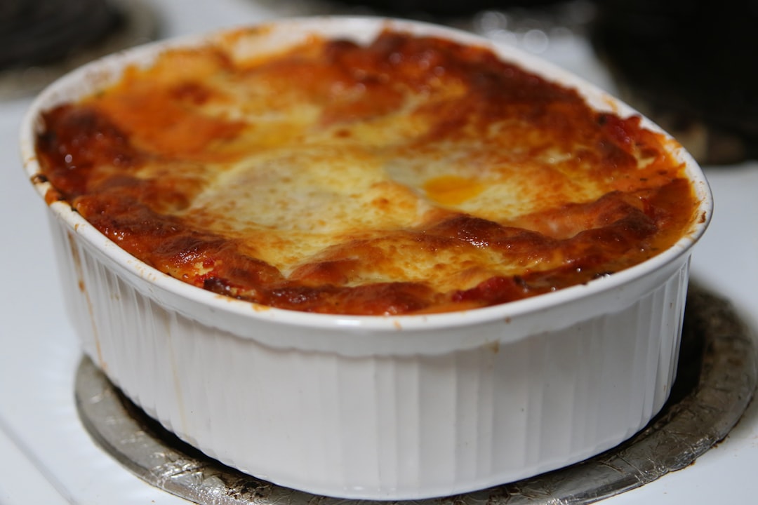 Baked Ziti — Classic Comfort Pasta with Ricotta, Mozzarella & Meat Sauce 26 golden bubbly baked ziti in a white ceramic baking dish, fresh basil on top, rustic wooden table