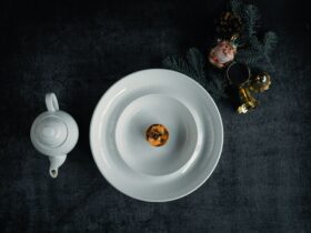 Bisque Cheesecake sliced and beautifully plated on a white ceramic plate with a smooth, creamy filling and golden graham cracker crust, garnished with a light dusting of spice and fresh herbs