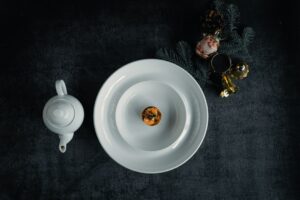 Bisque Cheesecake sliced and beautifully plated on a white ceramic plate with a smooth, creamy filling and golden graham cracker crust, garnished with a light dusting of spice and fresh herbs
