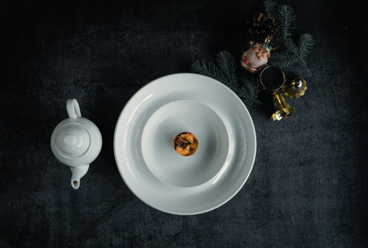 Bisque Cheesecake sliced and beautifully plated on a white ceramic plate with a smooth, creamy filling and golden graham cracker crust, garnished with a light dusting of spice and fresh herbs