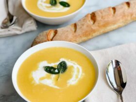 Butternut Squash Soup — Silky Roasted Squash Soup with Sage and Cream 36 Silky butternut squash soup in a white bowl topped with a swirl of cream, crispy sage leaves, and cracked black pepper, photographed overhead on a rustic wooden table with autumn leaves