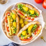 chicago style hot dog beautifully plated with all classic toppings on poppy seed bun, overhead shot on wooden board