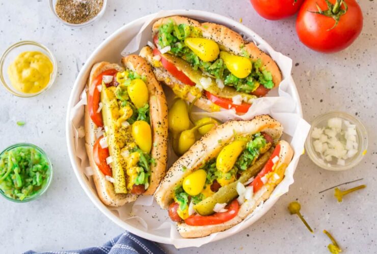 chicago style hot dog beautifully plated with all classic toppings on poppy seed bun, overhead shot on wooden board
