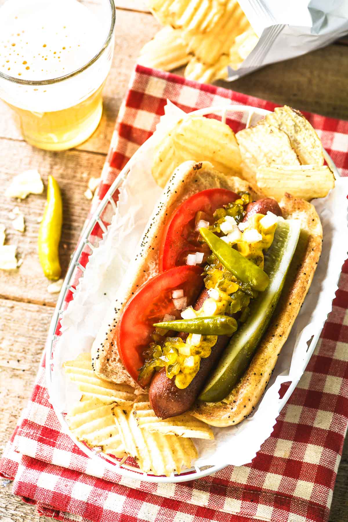 Chicago Style Hot Dogs — The Dragged Through the Garden Classic Done Right 28 close-up of Chicago style hot dog showing layers of toppings — tomato wedge, pickle spear, sport peppers, yellow mustard, relish, and celery salt on poppy seed bun