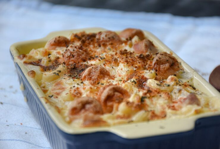Chicken Bacon Ranch Pasta Bake served in a white baking dish, golden and bubbling with melted cheddar, fresh chives on top, rustic wooden table background