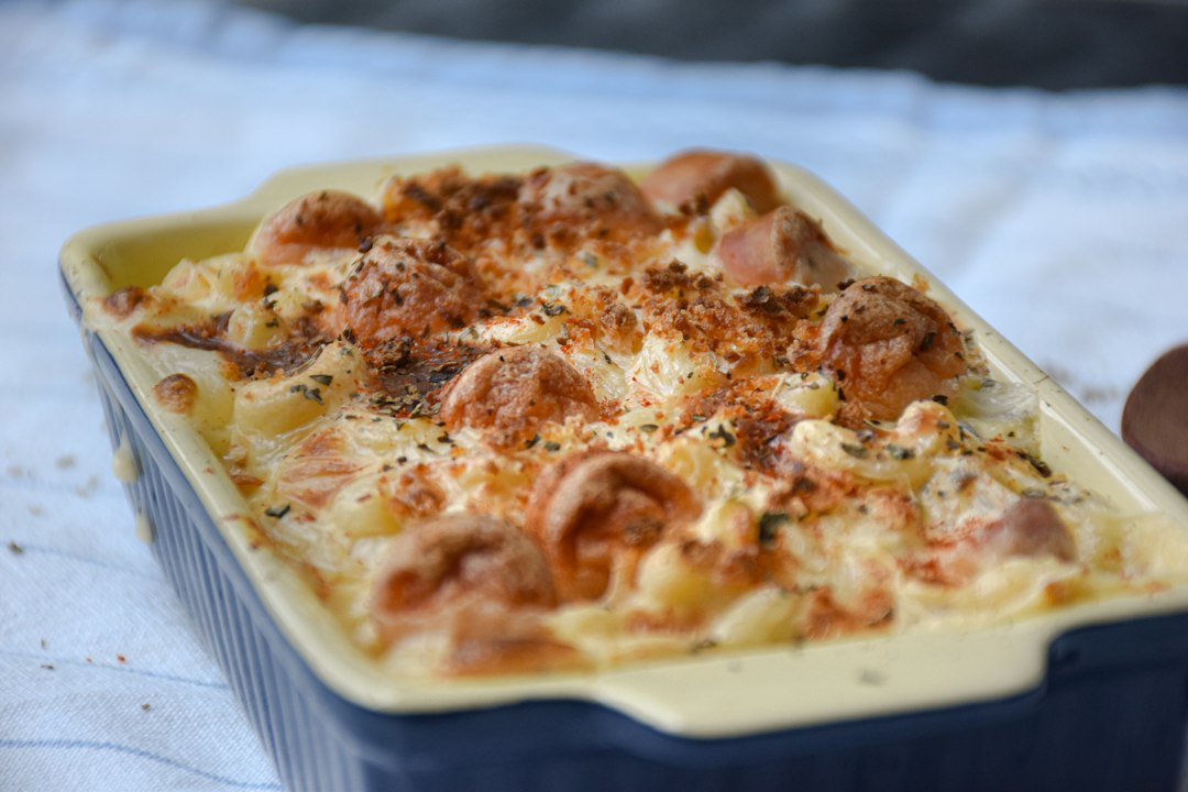 Chicken Bacon Ranch Pasta Bake served in a white baking dish, golden and bubbling with melted cheddar, fresh chives on top, rustic wooden table background