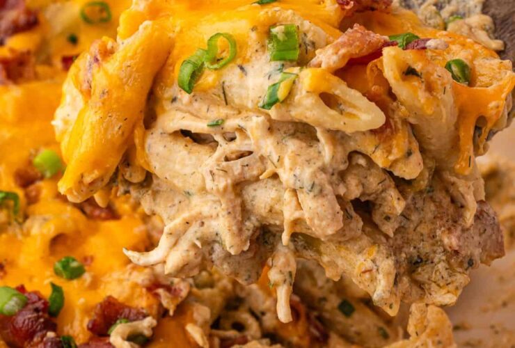 Chicken Bacon Ranch Pasta Bake served in a white baking dish, golden and bubbling with melted cheddar, fresh chives on top, rustic wooden table background