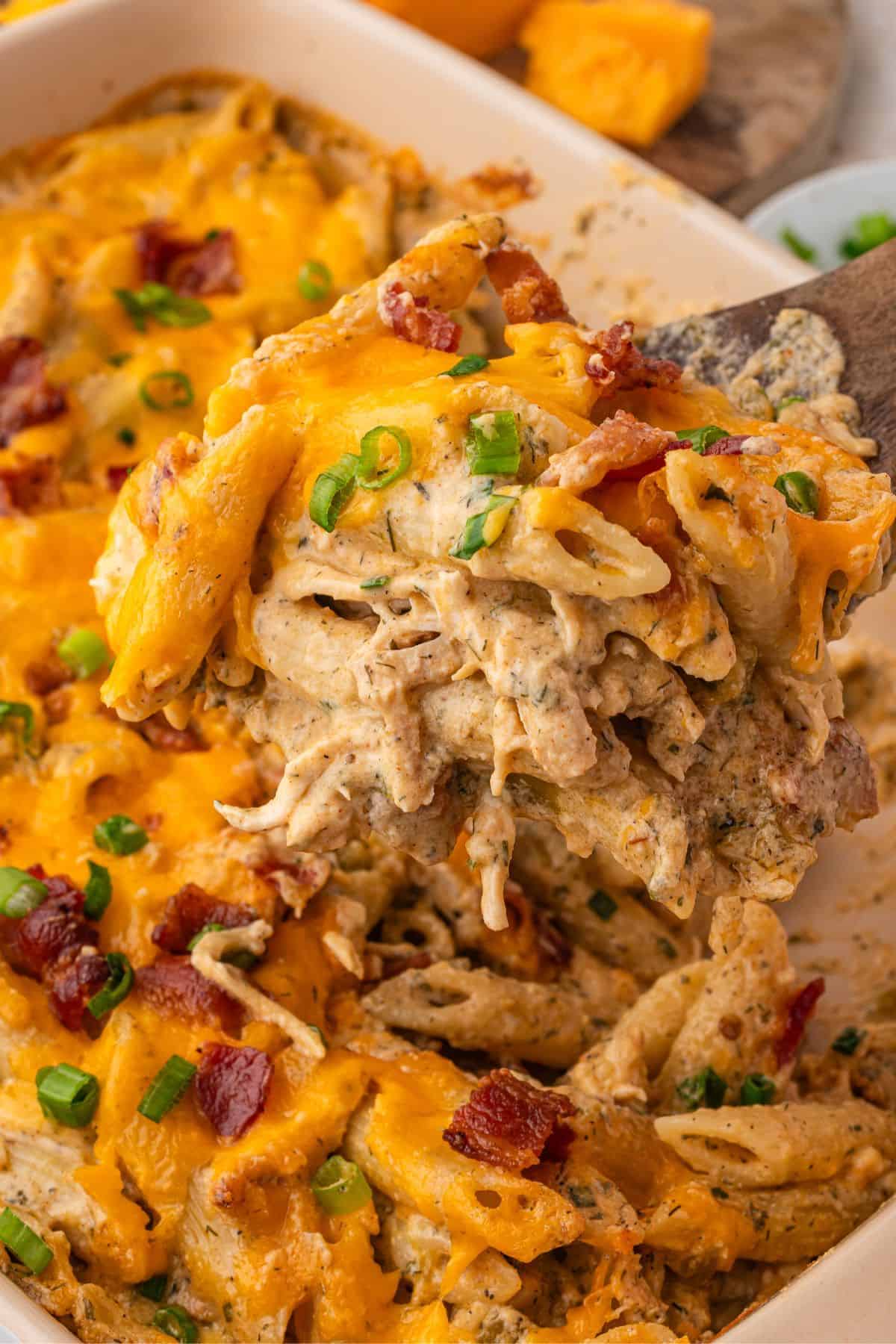 Chicken Bacon Ranch Pasta Bake — Creamy, Cheesy Comfort Food the Whole Family Will Love 26 Chicken Bacon Ranch Pasta Bake served in a white baking dish, golden and bubbling with melted cheddar, fresh chives on top, rustic wooden table background