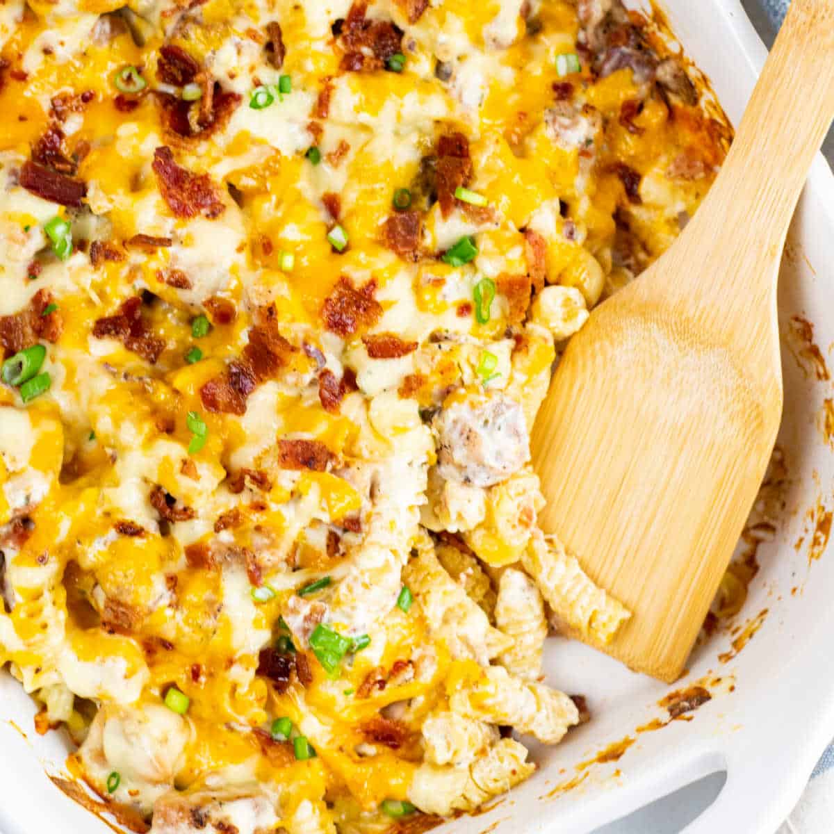 Chicken Bacon Ranch Pasta Bake — Creamy, Cheesy Comfort Food the Whole Family Will Love 28 Close-up of a spoonful of Chicken Bacon Ranch Pasta Bake being lifted from the dish, showing creamy sauce, chunks of chicken, crispy bacon, and melted cheddar stretching
