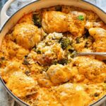 Chicken broccoli rice casserole in a white baking dish, golden cheesy top, fresh out of the oven on a wooden table