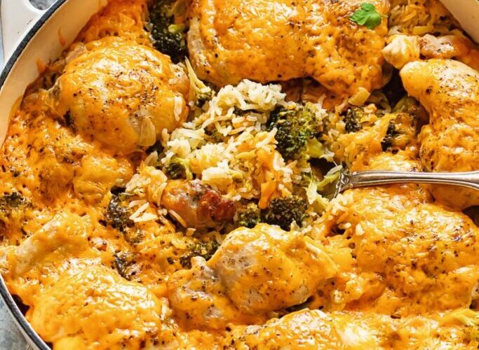 Chicken broccoli rice casserole in a white baking dish, golden cheesy top, fresh out of the oven on a wooden table