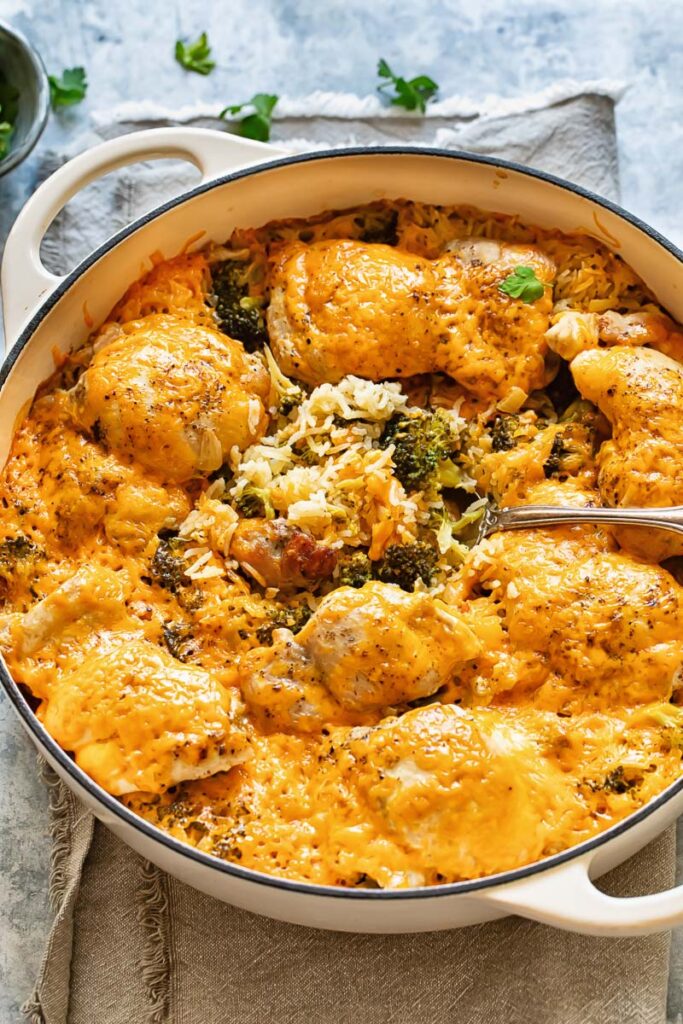 Chicken broccoli rice casserole in a white baking dish, golden cheesy top, fresh out of the oven on a wooden table