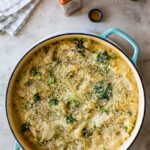 overhead shot of chicken broccoli rice casserole golden and bubbly fresh from the oven in a white baking dish, garnished with fresh parsley