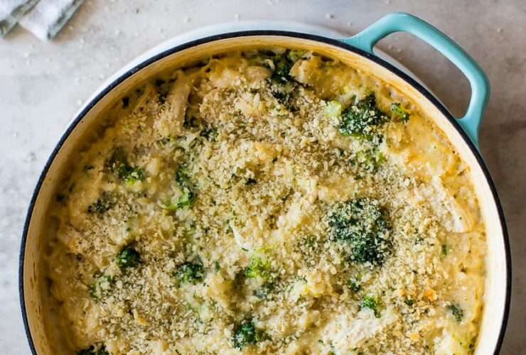overhead shot of chicken broccoli rice casserole golden and bubbly fresh from the oven in a white baking dish, garnished with fresh parsley