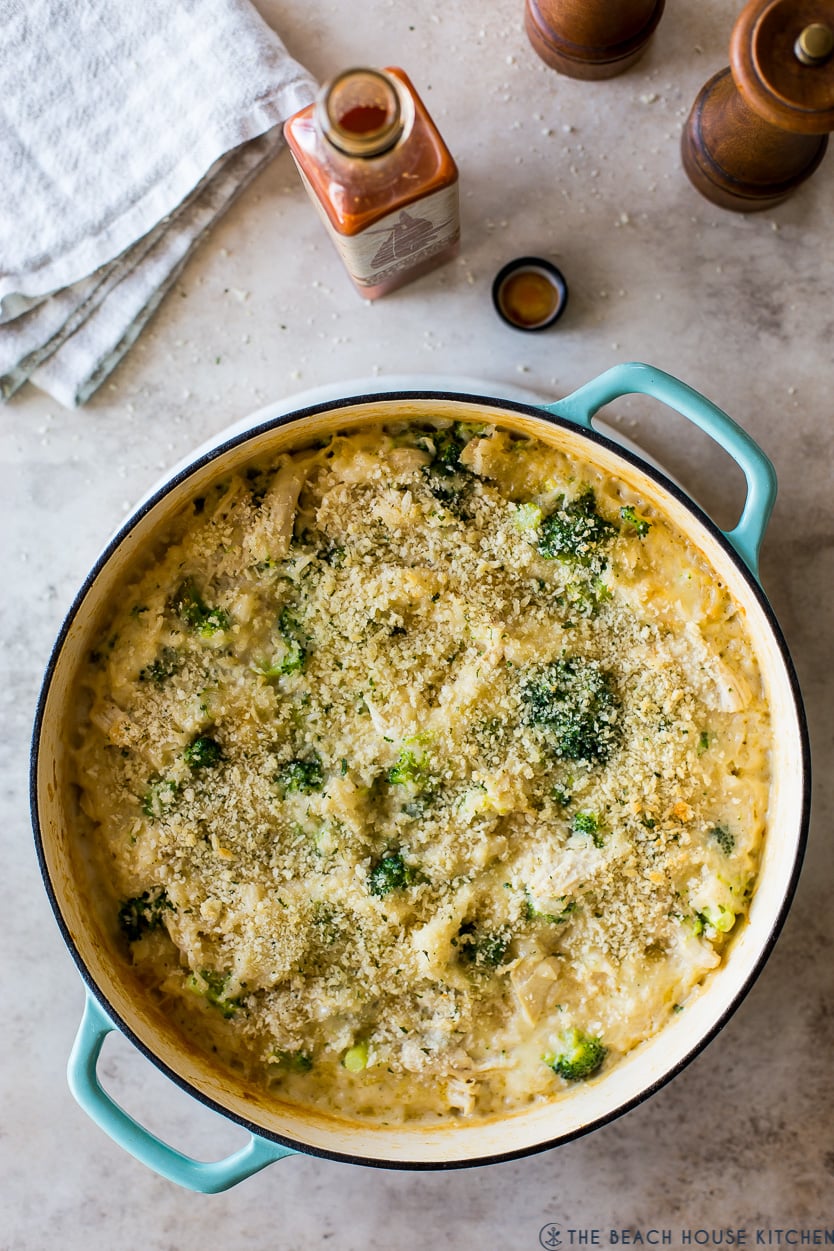 overhead shot of chicken broccoli rice casserole golden and bubbly fresh from the oven in a white baking dish, garnished with fresh parsley