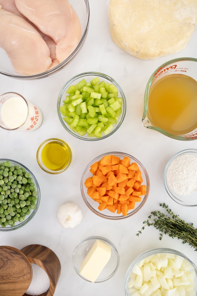 Chicken Pot Pie — Creamy Filling, Flaky Double Crust, Pure Comfort 27 overhead shot of chicken pot pie ingredients laid out on a marble surface — diced carrots, peas, raw chicken, fresh thyme, pie crust dough, butter, and chicken broth