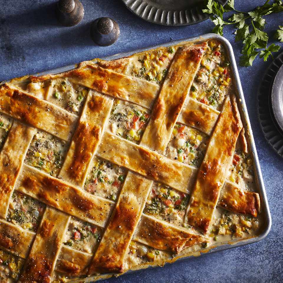 overhead shot of chicken pot pie ingredients laid out — diced chicken, chopped carrots, peas, celery, onion, fresh herbs, butter, and pie crust on a marble countertop