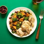 golden chicken pot pie casserole in a white baking dish with fluffy biscuit topping, garnished with fresh thyme