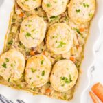 golden chicken pot pie casserole in a white baking dish with fluffy biscuit topping, garnished with fresh thyme