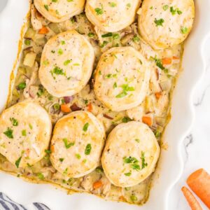 golden chicken pot pie casserole in a white baking dish with fluffy biscuit topping, garnished with fresh thyme