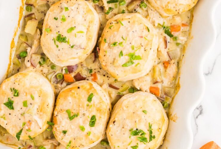 golden chicken pot pie casserole in a white baking dish with fluffy biscuit topping, garnished with fresh thyme