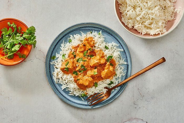 Chicken Tikka Masala — Rich, Aromatic, and Deeply Satisfying 26 Chicken Tikka Masala served in a white bowl over fluffy basmati rice, garnished with fresh cilantro and a swirl of cream, photographed from above on a warm wooden table