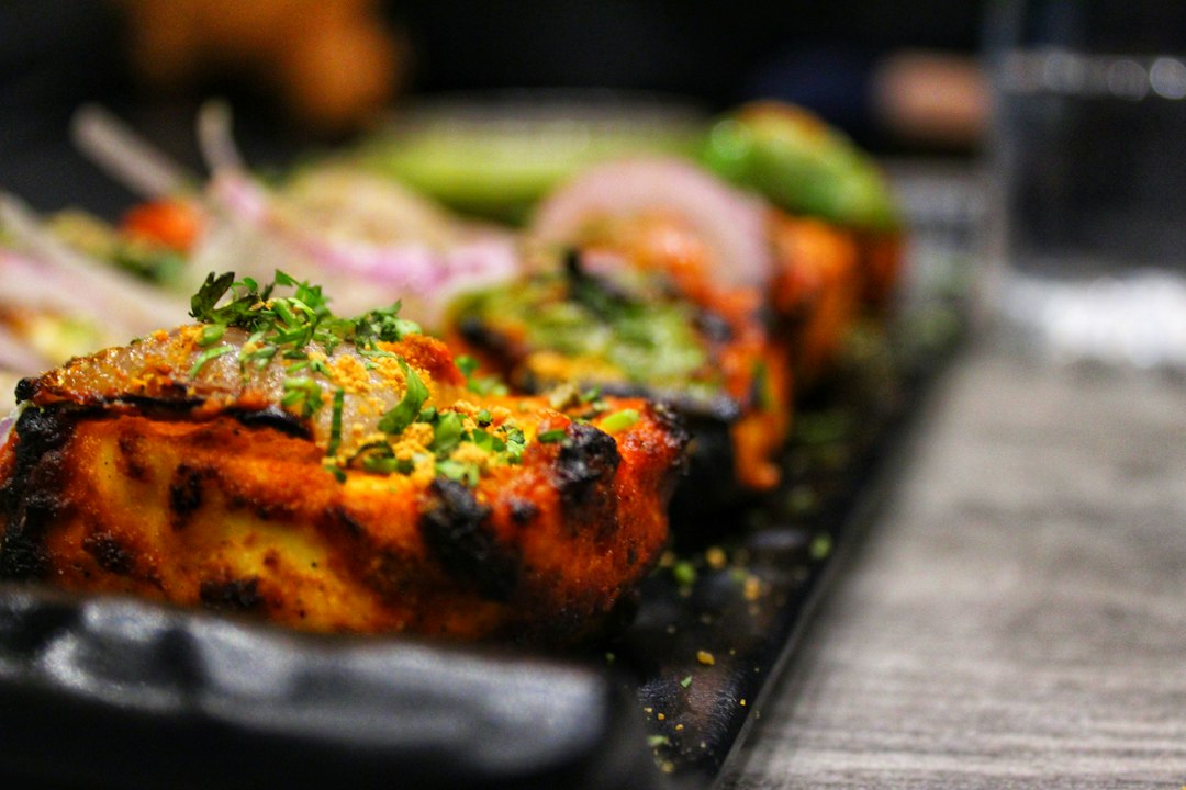 Chicken Tikka Masala — Rich, Aromatic, and Deeply Satisfying 25 Close-up of Chicken Tikka Masala sauce coating tender pieces of charred chicken, with fresh cilantro leaves and a slice of warm naan on the side, shallow depth of field