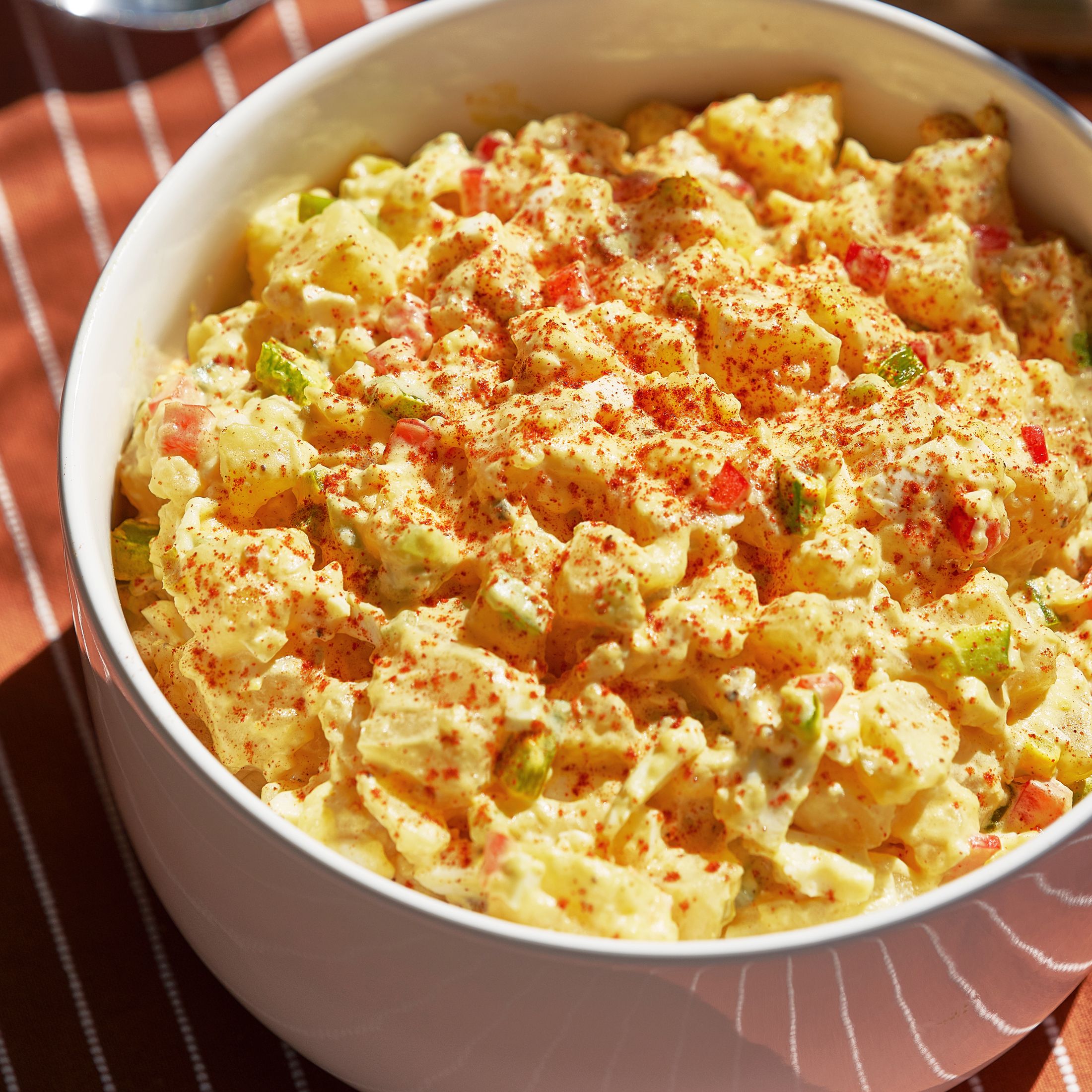 Close-up of Classic Potato Salad in a serving spoon showing creamy dressing, egg chunks, and paprika garnish