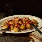 Coq au Vin served in a wide shallow bowl with tender chicken thighs, mushrooms, pearl onions, and glossy red wine sauce, garnished with fresh thyme