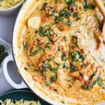 Creamy Tuscan Chicken served in a white skillet with golden pan-seared chicken breasts nestled in a rich spinach and sun-dried tomato cream sauce, garnished with fresh basil