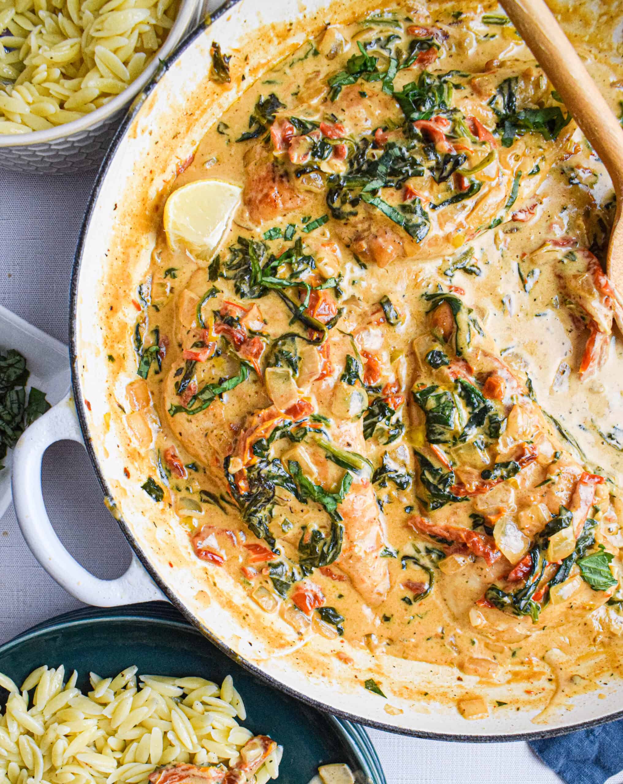 Creamy Tuscan Chicken served in a white skillet with golden pan-seared chicken breasts nestled in a rich spinach and sun-dried tomato cream sauce, garnished with fresh basil