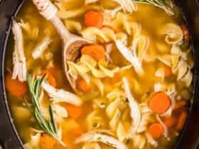 Crockpot Chicken Noodle Soup — The Ultimate From-Scratch Slow Cooker Comfort Bowl 36 A steaming bowl of Crockpot Chicken Noodle Soup with golden broth, tender shredded chicken, thick egg noodles, and sliced carrots, garnished with fresh parsley, photographed overhead on a rustic wooden table