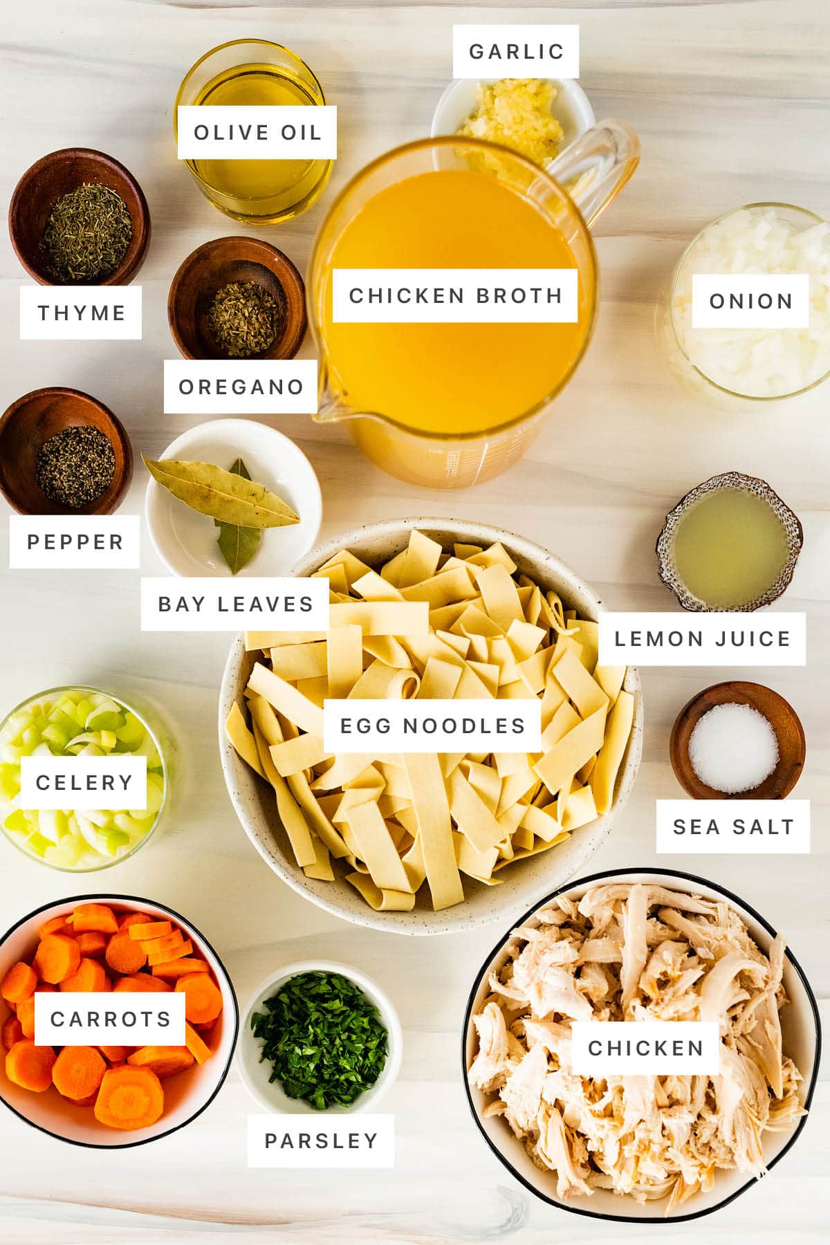 Crockpot Chicken Noodle Soup — The Ultimate From-Scratch Slow Cooker Comfort Bowl 27 Overhead flat-lay of crockpot chicken noodle soup ingredients laid out on a marble surface — bone-in chicken pieces, whole carrots, celery stalks, onion, garlic cloves, fresh thyme, bay leaves, and dry egg noodles
