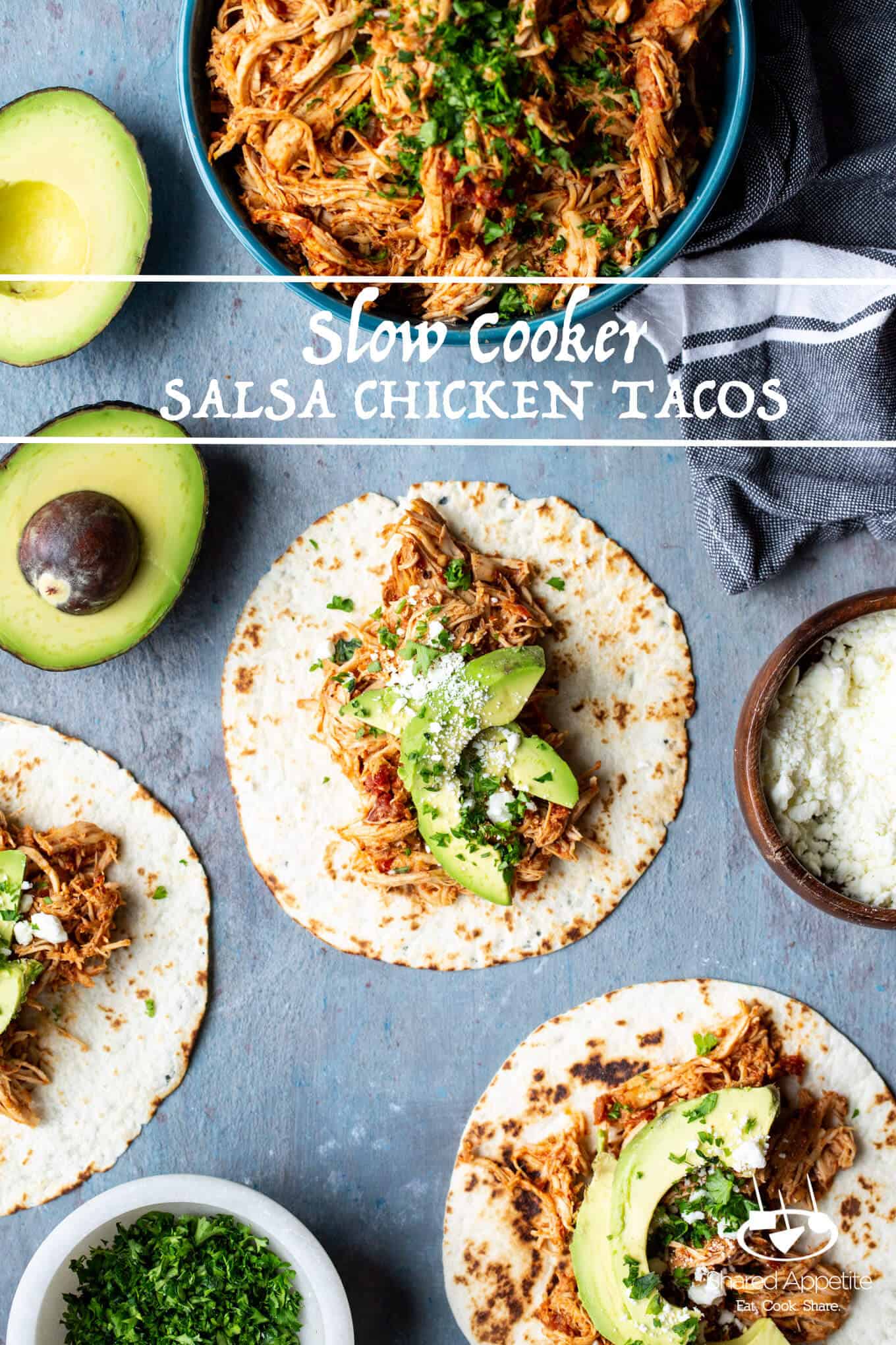 Overhead flat-lay of raw chicken breasts in a slow cooker insert surrounded by a jar of chunky salsa, taco seasoning, lime, and fresh cilantro on a white marble surface