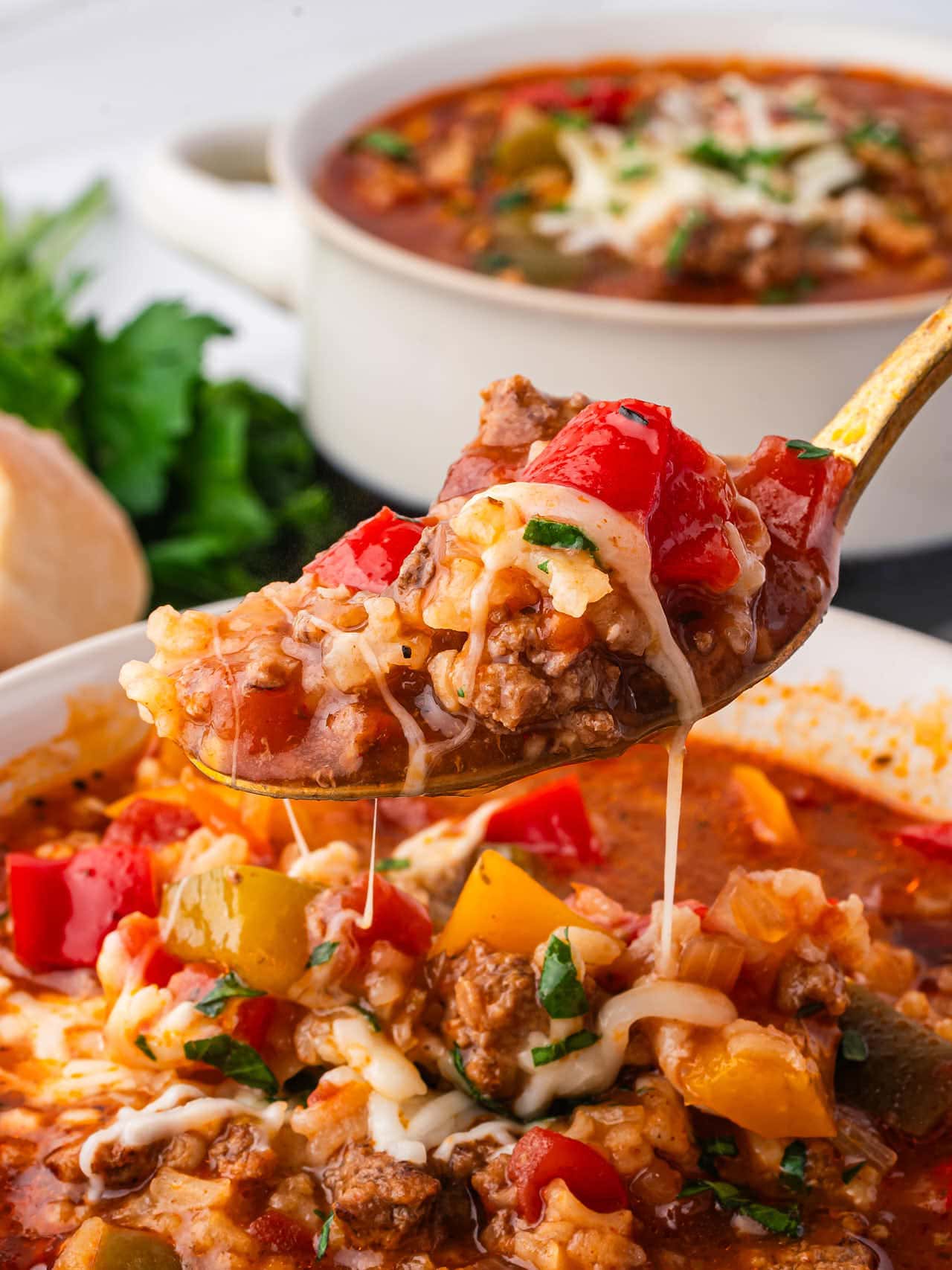 Crockpot Stuffed Pepper Soup — All the Flavor, None of the Fuss 28 A close-up shot of a spoonful of Crockpot Stuffed Pepper Soup being lifted from a rustic bowl, showing colorful pepper chunks, ground beef, rice, and glossy tomato broth with melted cheese on top