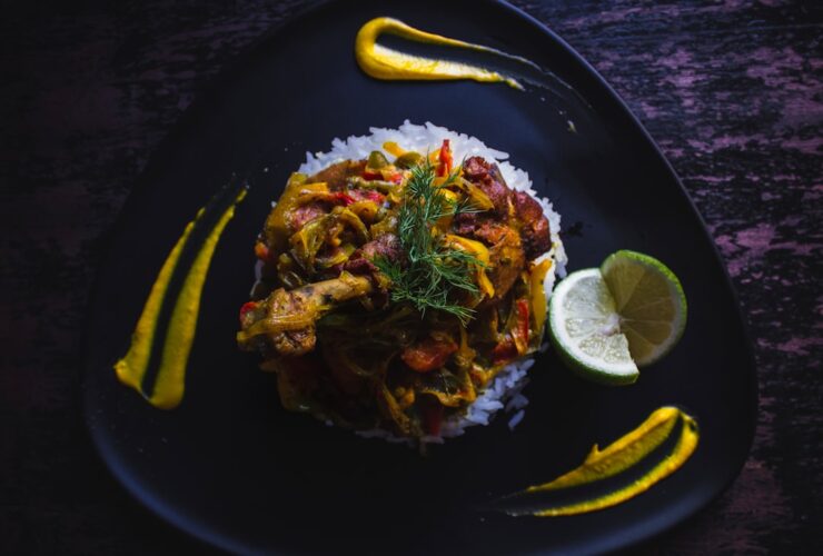 Cuban Ropa Vieja served over white rice in a wide bowl, topped with fresh cilantro and sliced olives, photographed on a rustic wooden table with warm lighting