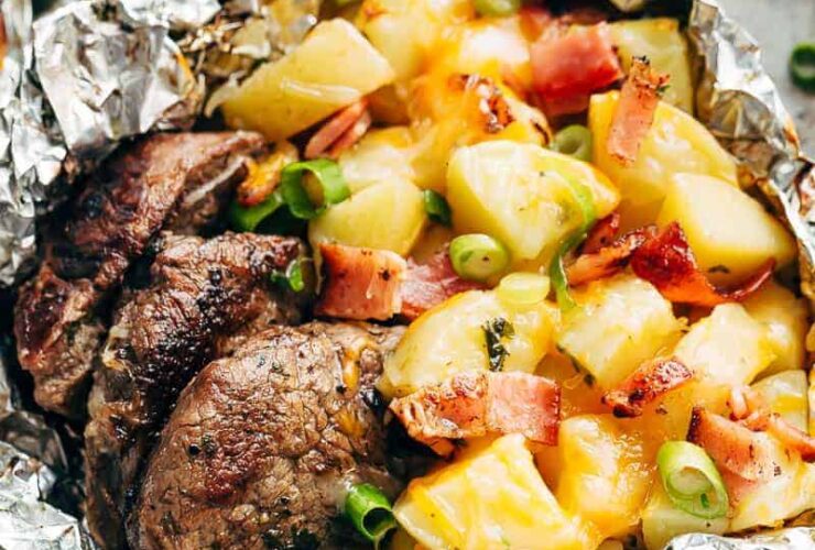 Foil Packet Steak and Potato Hash beautifully served open on a plate with juices pooling around tender steak, golden potatoes, and crispy bacon pieces, garnished with fresh herbs