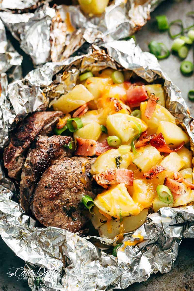 Step-by-step flat lay of Foil Packet Steak and Potato Hash ingredients laid out on a wooden board — cubed sirloin, halved baby potatoes, chopped bacon, butter pats, garlic, smoked paprika, and fresh thyme before assembly