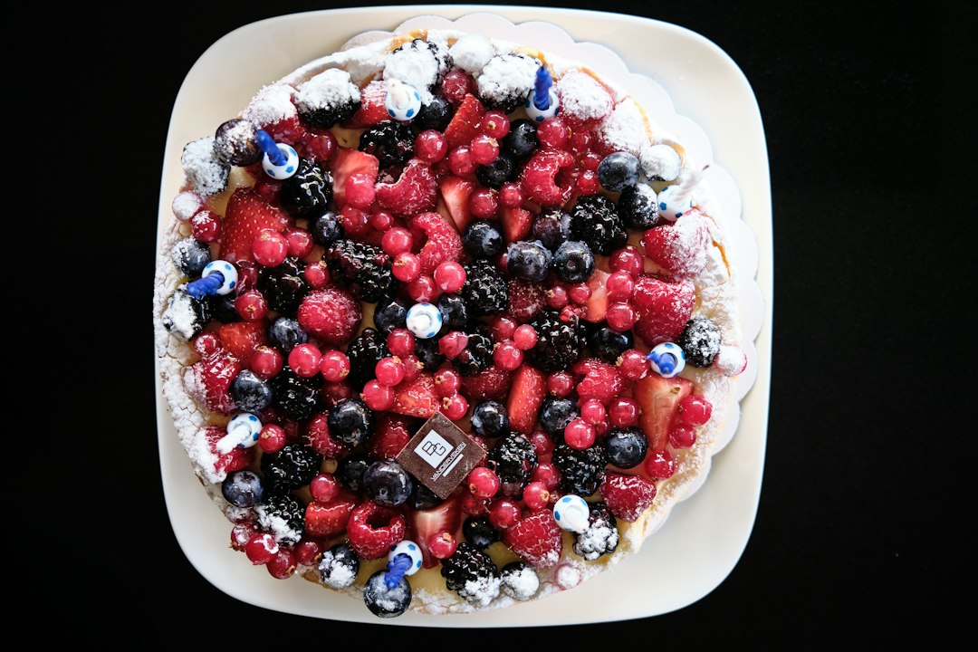 Frozen Greek yogurt berry bark broken into pieces on a white marble surface, topped with fresh strawberries, blueberries, and raspberries, drizzled with honey, bright natural lighting