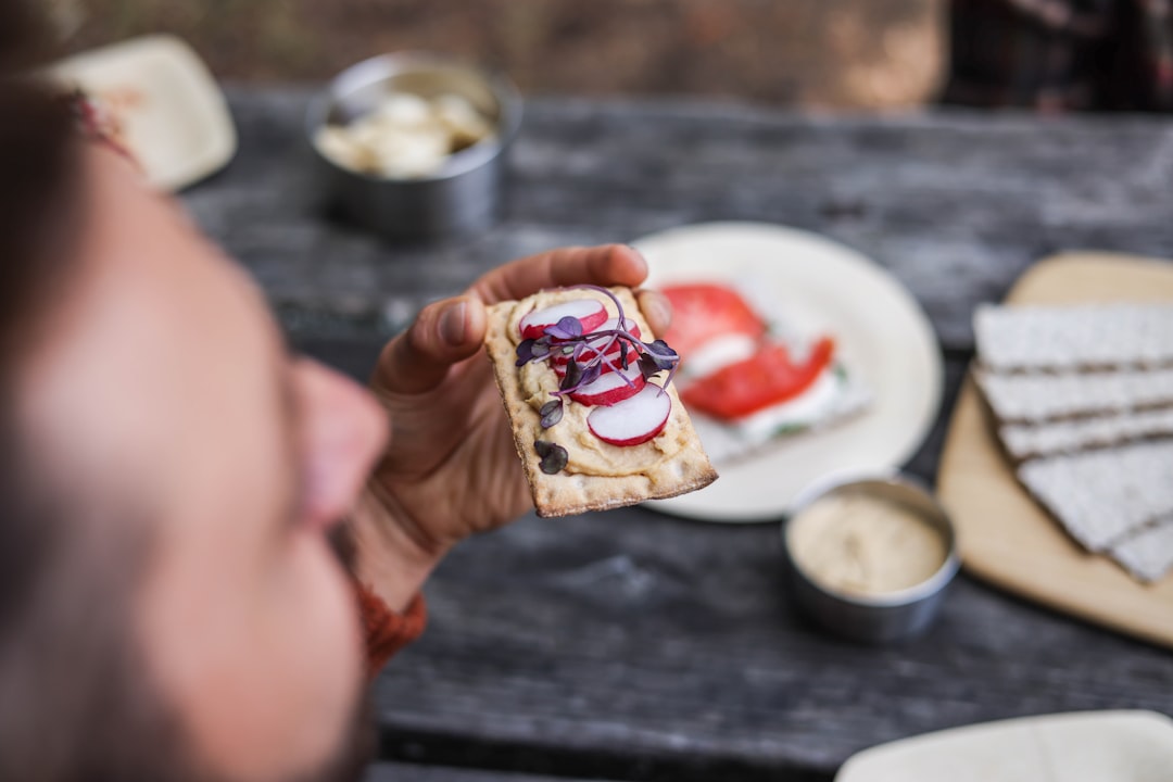 Close-up of a hand holding a broken piece of frozen Greek yogurt berry bark showing the creamy yogurt interior studded with bright berries and crunchy granola, soft natural light background