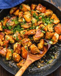Garlic Butter Chicken Bites and Potatoes — Skillet Dinner Ready in 25 Minutes 13 Garlic Butter Chicken Bites and Potatoes served in a cast iron skillet, garnished with fresh parsley and lemon wedges on a rustic wooden table