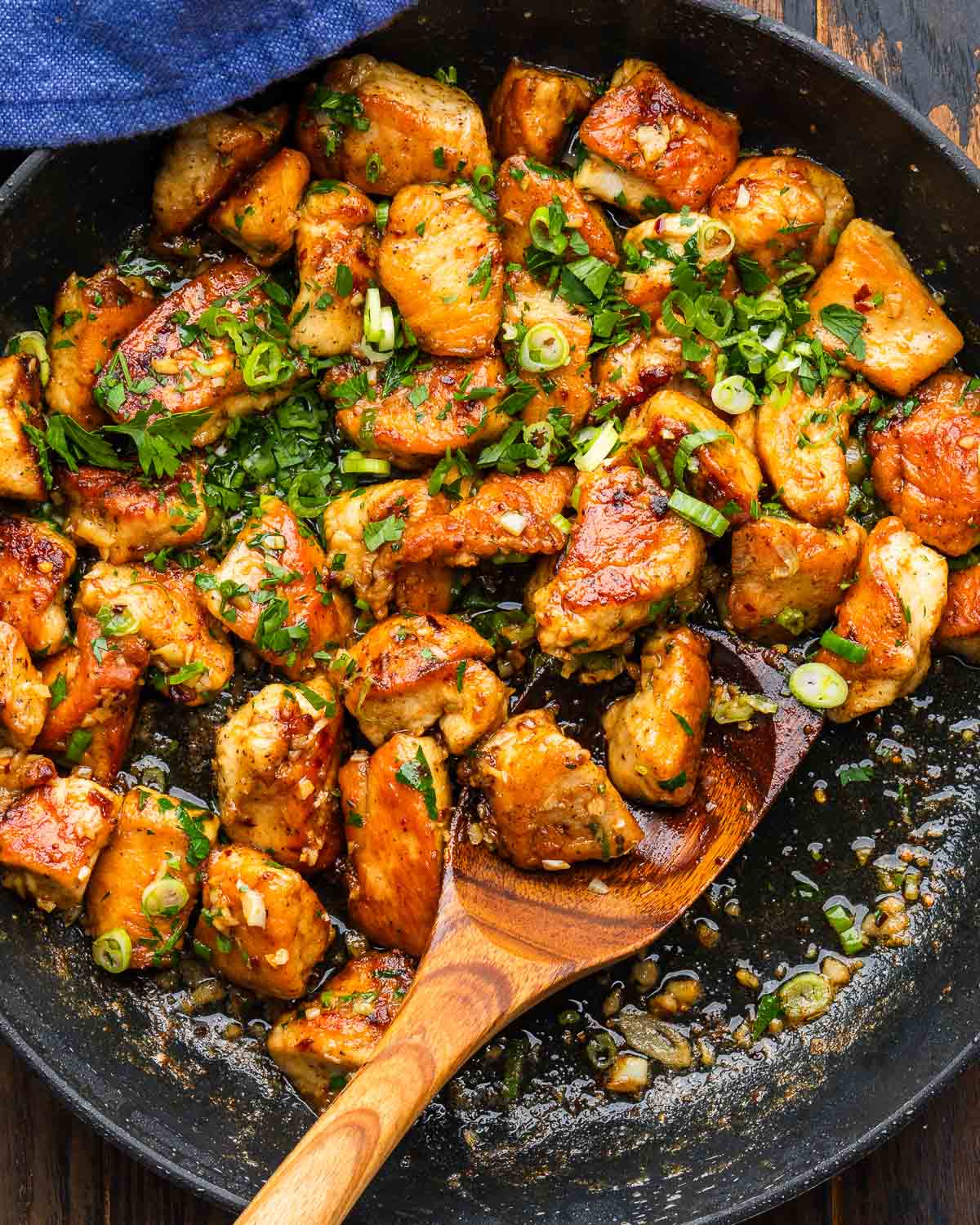 Garlic Butter Chicken Bites and Potatoes served in a cast iron skillet, garnished with fresh parsley and lemon wedges on a rustic wooden table
