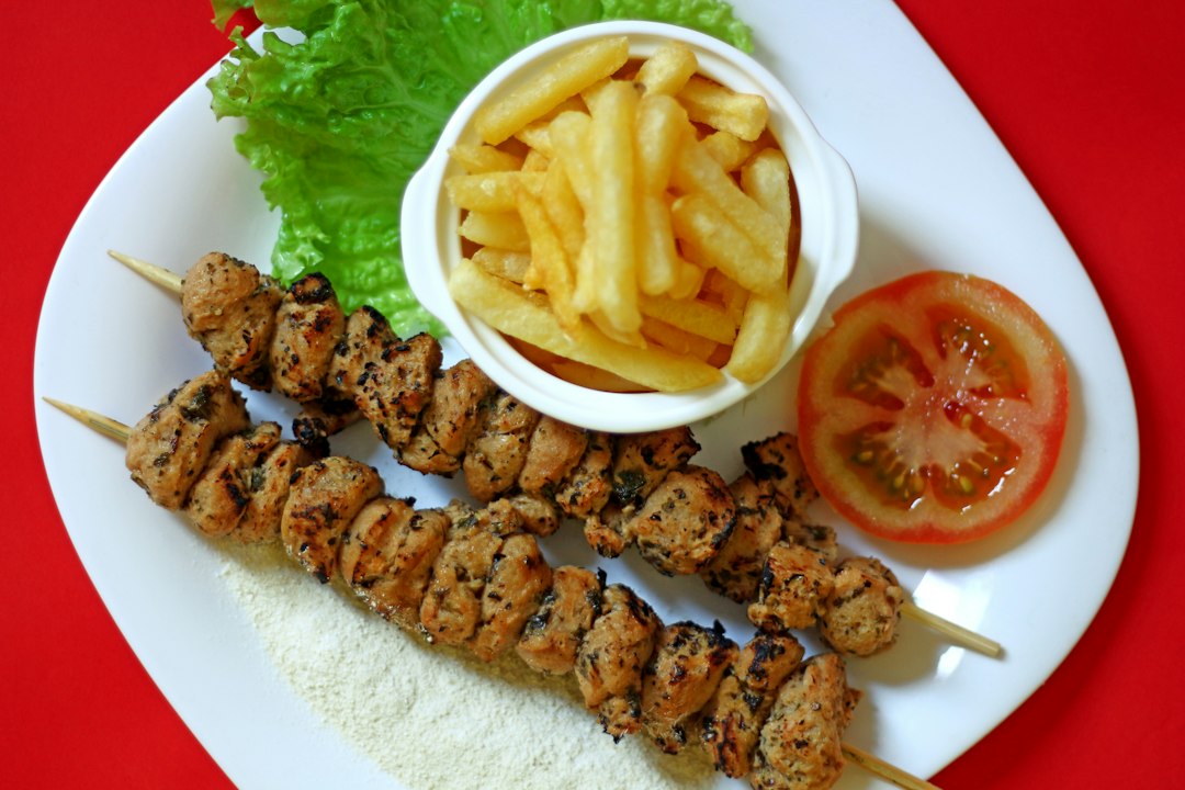 Greek Chicken Souvlaki served on a platter with warm pita, tzatziki, sliced tomatoes, red onion, and fresh parsley garnish