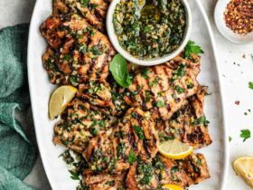Grilled Chicken Thighs — The Juicy, Flavor-Packed Weeknight Grill Staple You'll Make on Repeat 39 Perfectly grilled chicken thighs on a white plate with fresh herbs and lemon wedges, beautifully charred grill marks visible
