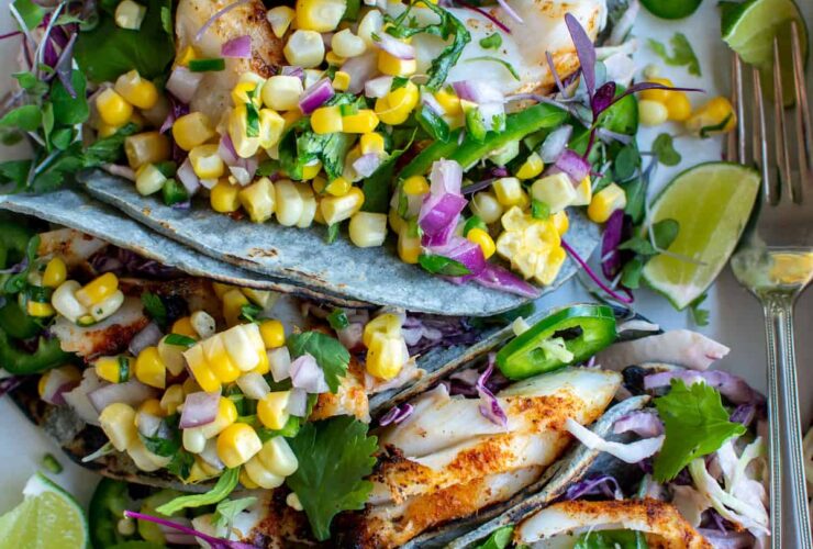 Grilled Fish Tacos with Corn Salsa plated beautifully on a wooden board with lime wedges, fresh cilantro, and charred corn salsa