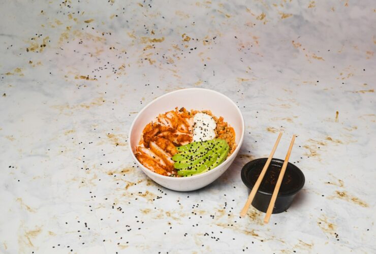 Hawaiian poke bowl with sushi-grade ahi tuna, steamed rice, edamame, cucumber, avocado, and sesame seeds in a white ceramic bowl, overhead shot, bright natural light