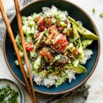 Hawaiian poke bowl with sushi-grade ahi tuna, steamed rice, edamame, cucumber, avocado, and sesame seeds in a white ceramic bowl, overhead shot, bright natural light
