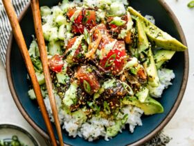 Hawaiian poke bowl with sushi-grade ahi tuna, steamed rice, edamame, cucumber, avocado, and sesame seeds in a white ceramic bowl, overhead shot, bright natural light