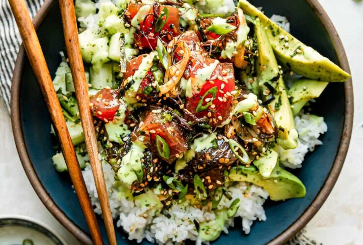 Hawaiian poke bowl with sushi-grade ahi tuna, steamed rice, edamame, cucumber, avocado, and sesame seeds in a white ceramic bowl, overhead shot, bright natural light