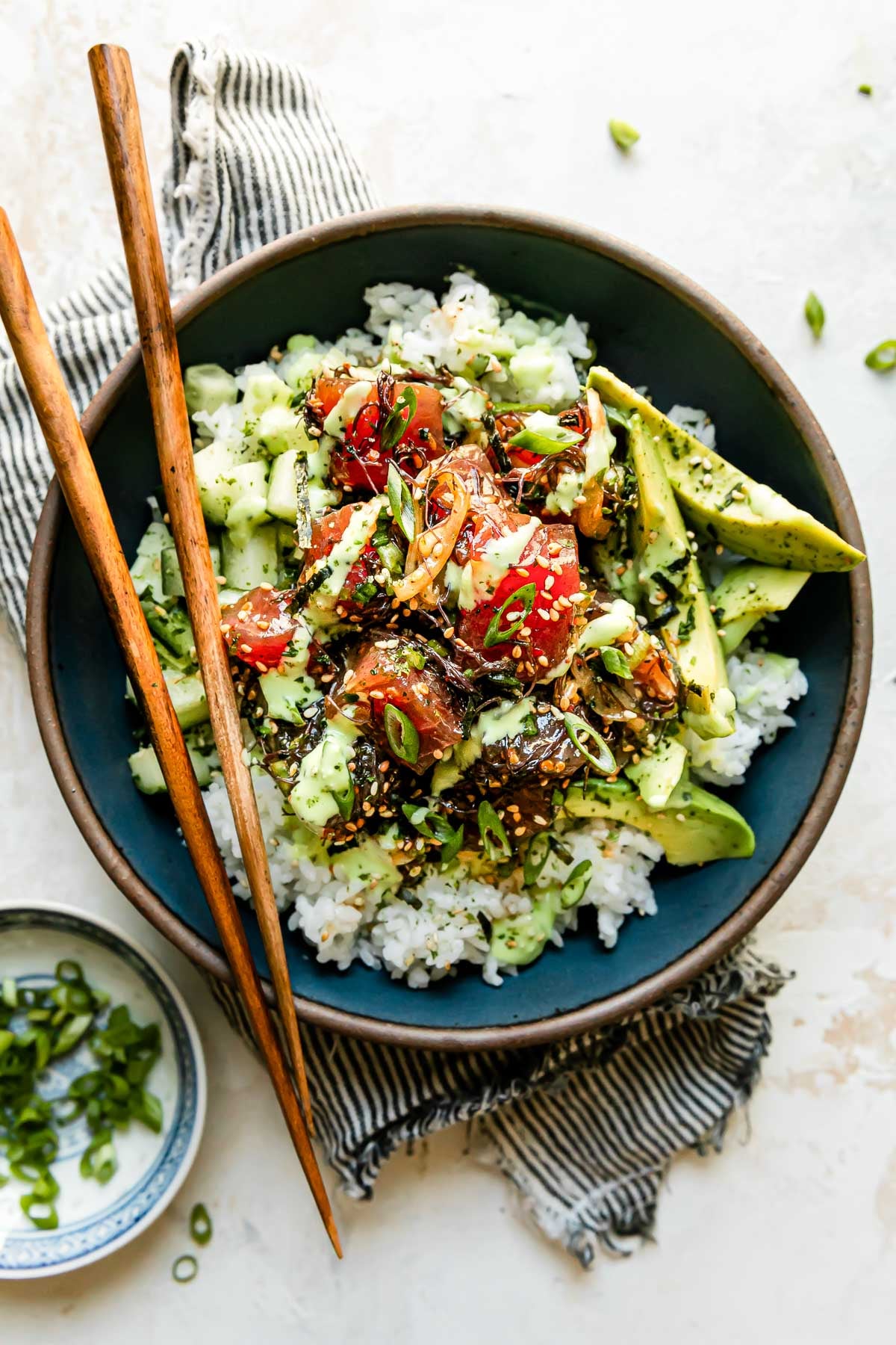 Hawaiian poke bowl with sushi-grade ahi tuna, steamed rice, edamame, cucumber, avocado, and sesame seeds in a white ceramic bowl, overhead shot, bright natural light